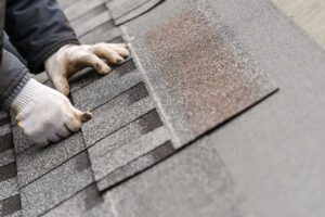 Technicians installing new roofing materials and checking digital monitoring equipment on a residential roof.