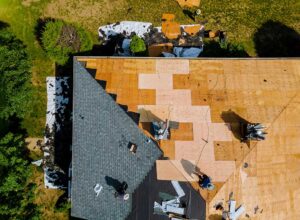 Attic framing with plywood roof decking, insulation, and a visible water stain near a roof opening.