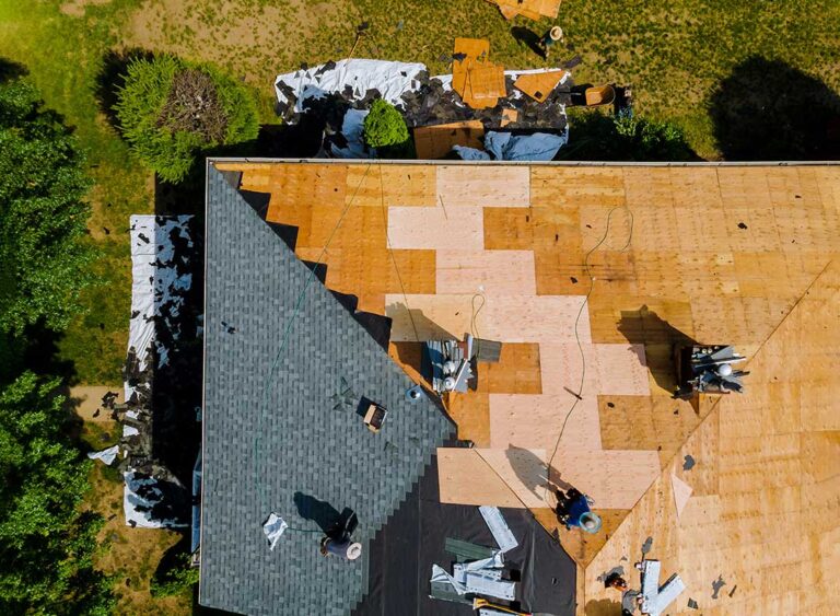 Attic framing with plywood roof decking, insulation, and a visible water stain near a roof opening.